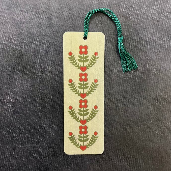 A light wood bookmark with a teal tassel featuring an image of red flowers, leaves, and hearts. Sold at Coyote Supply Co a BIPOC and LGBTQIA+ owned zero waste witch store in Reno Nevada