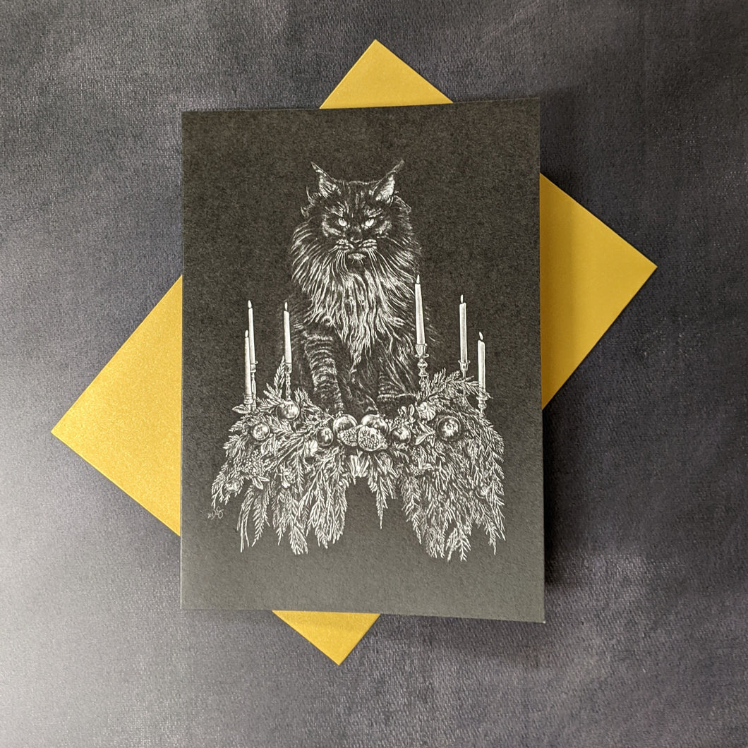 A black card with a monochrome illustration of a Norwegian forest cat standing on a bed of holiday plants and candles by Death of Seasons against a yellow envelope. Sold at Coyote Supply Co a BIPOC and LGBTQIA+ owned zero waste witch store in Reno Nevada 