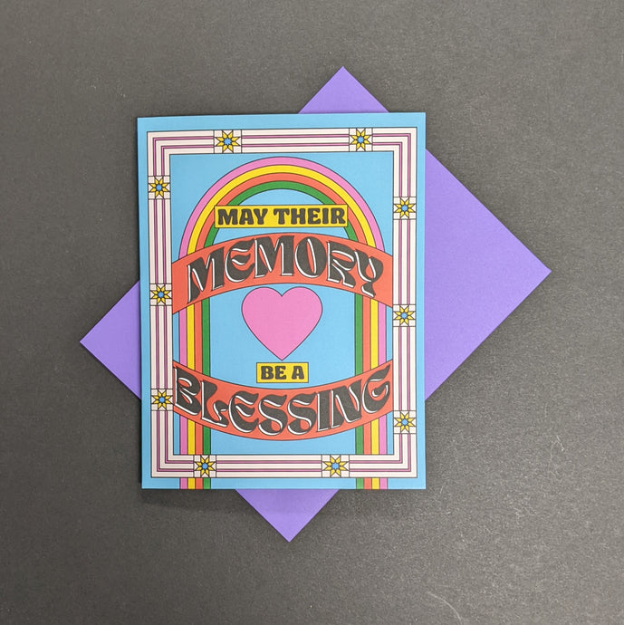 A blue greeting card with a rainbow and heart with text that reads: May their memory be a blessing.  Sold at Coyote Supply Co a BIPOC and LGBTQIA+ owned zero waste witch store in Reno Nevada 